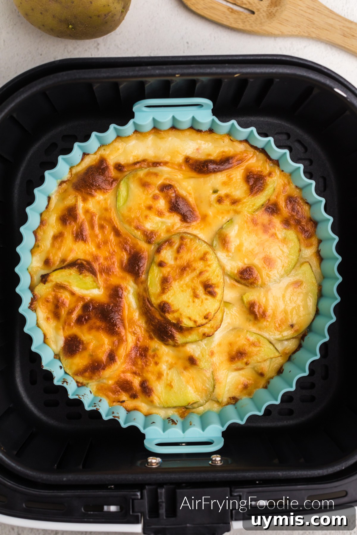 Air Fryer Scalloped Potatoes with Melted Cheese 10 Air fryer scalloped potatoes in the basket of the air fryer.