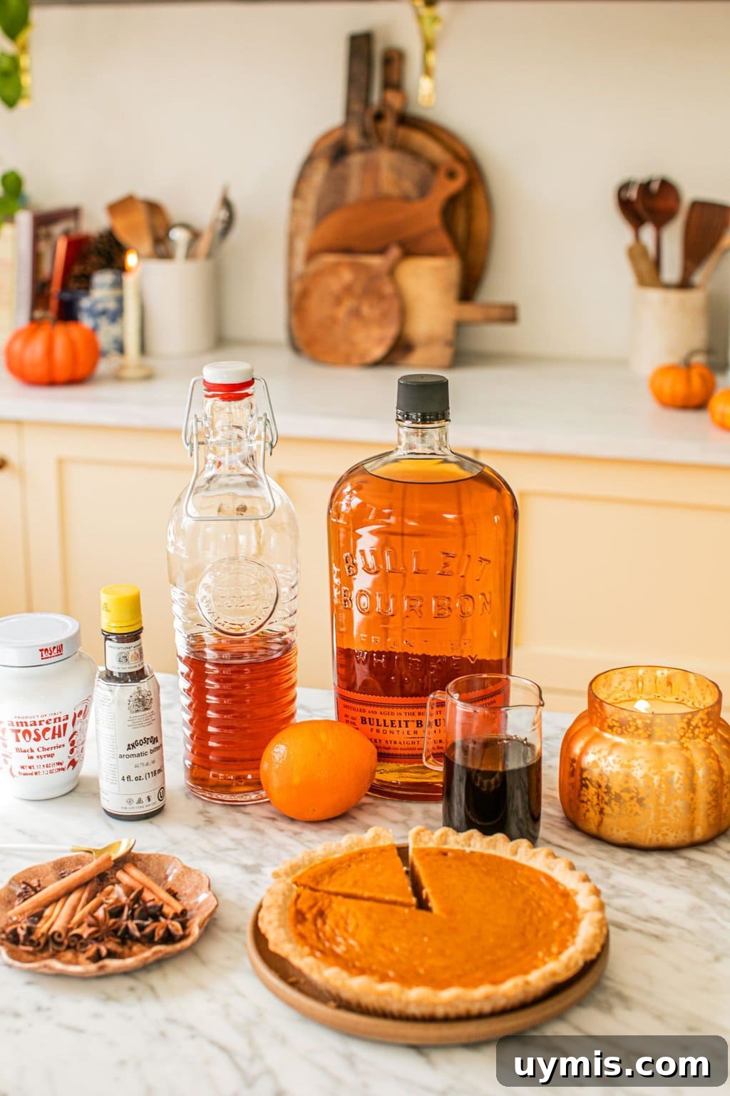 bourbon, simple syrup, aromatic bitters, oranges, a candle, cinnamon sticks, star anise, and a pumpkin pie