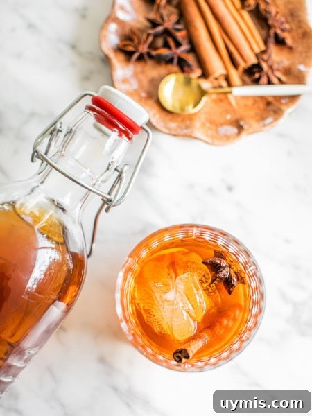 an old fashioned photographed from above with a swing top bottle hovering above and a small plate with garnish in the top right corner of the photo