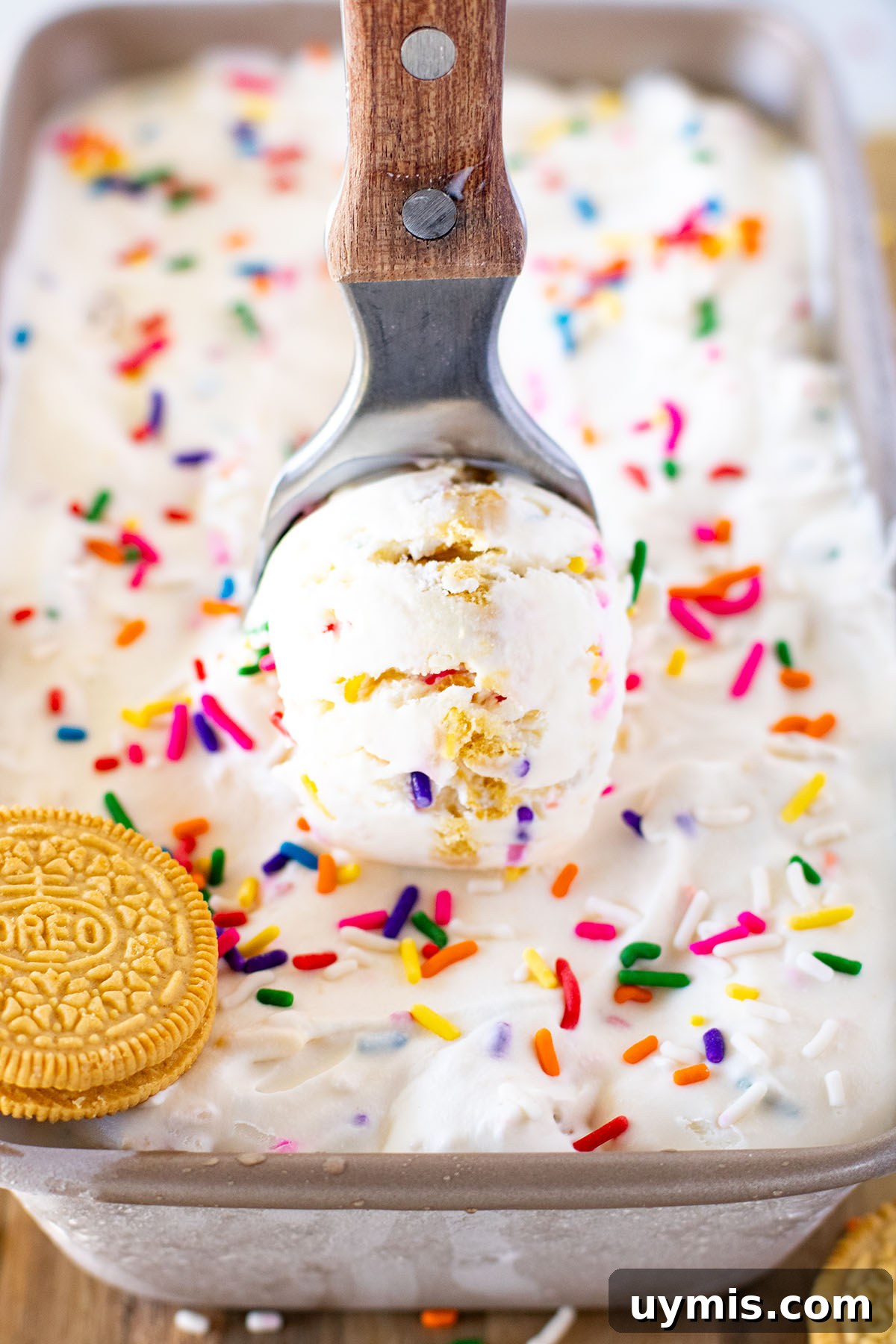 No-Churn Funfetti Golden Oreo Ice Cream Recipe 9 A scoop of Funfetti Golden Oreo Ice Cream being served out of the frozen ice cream in a metal loaf pan.