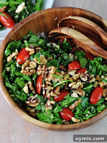 Wood serving bowl of arugula feta tomato salad.