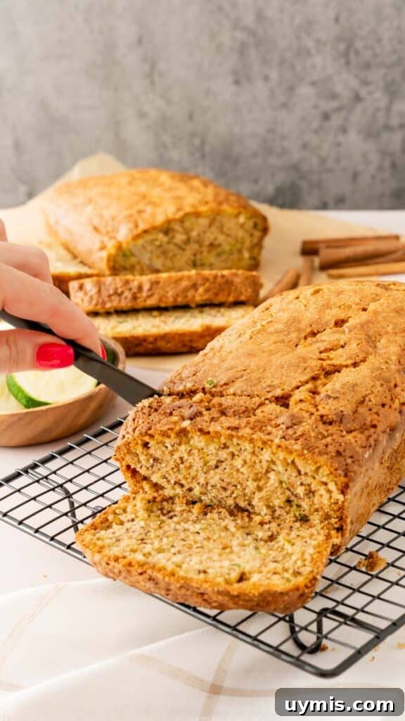 Moist Banana Zucchini Bread Recipe 5 A black knife slicing a freshly baked banana zucchini bread loaf.