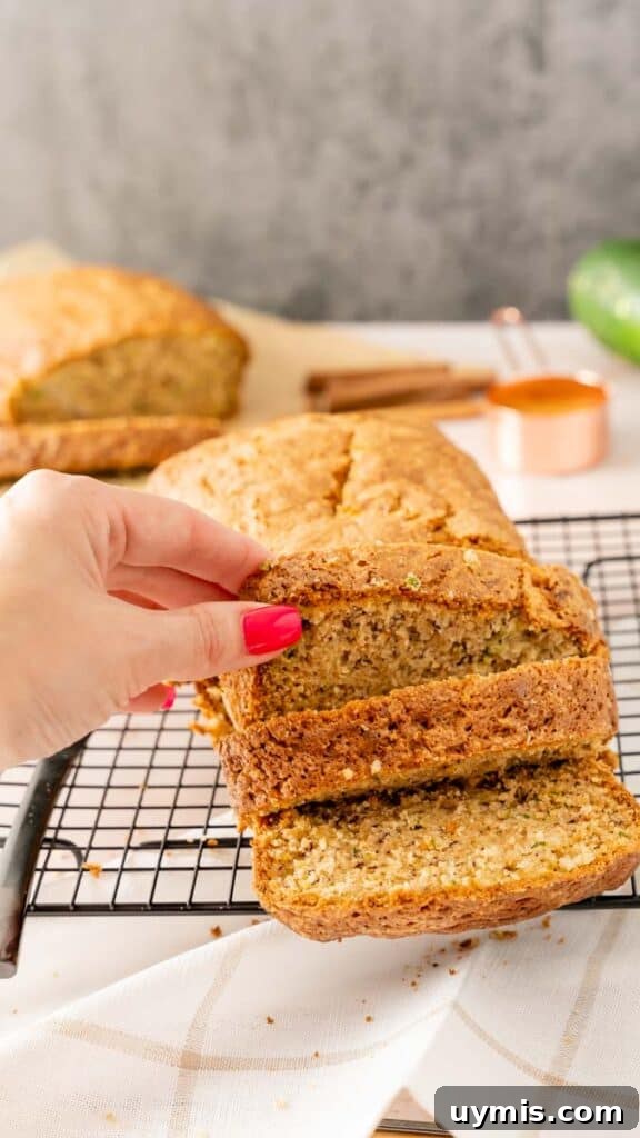 Moist Banana Zucchini Bread Recipe 6 A manicured hand lifting a slice of banana bread from the sliced loaf.