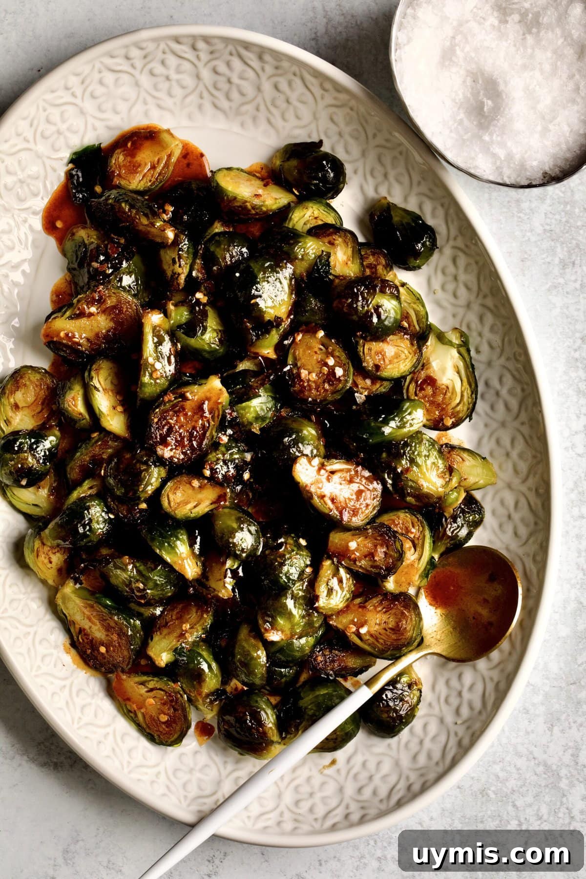 LongHorn Steakhouse Copycat Crispy Brussels Sprouts Recipe 10 Crispy Brussels Sprouts Recipe on a cream colored serving platter. with serving spoon
