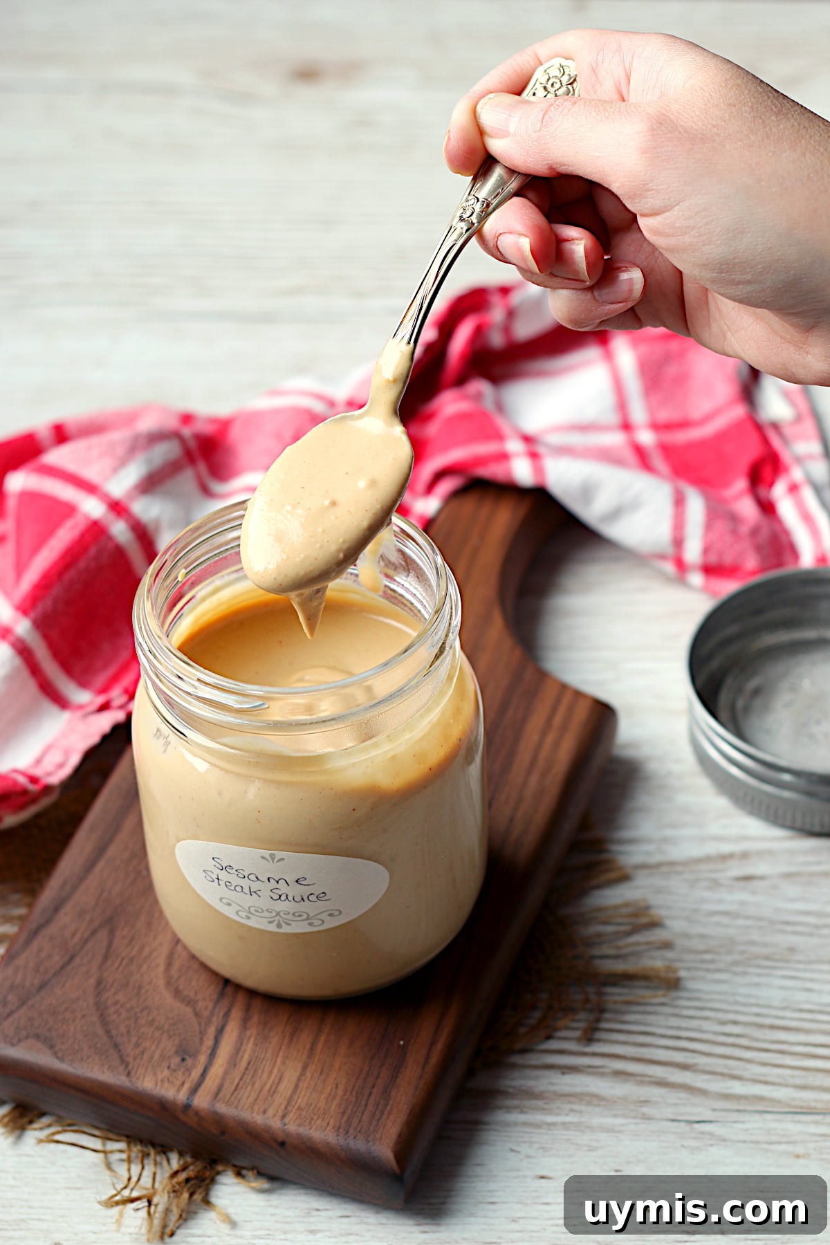 Sesame Steak Sauce Recipe Sawmill Copycat 3 A spoon scooping a spoonful of sesame steak sauce from a jar.
