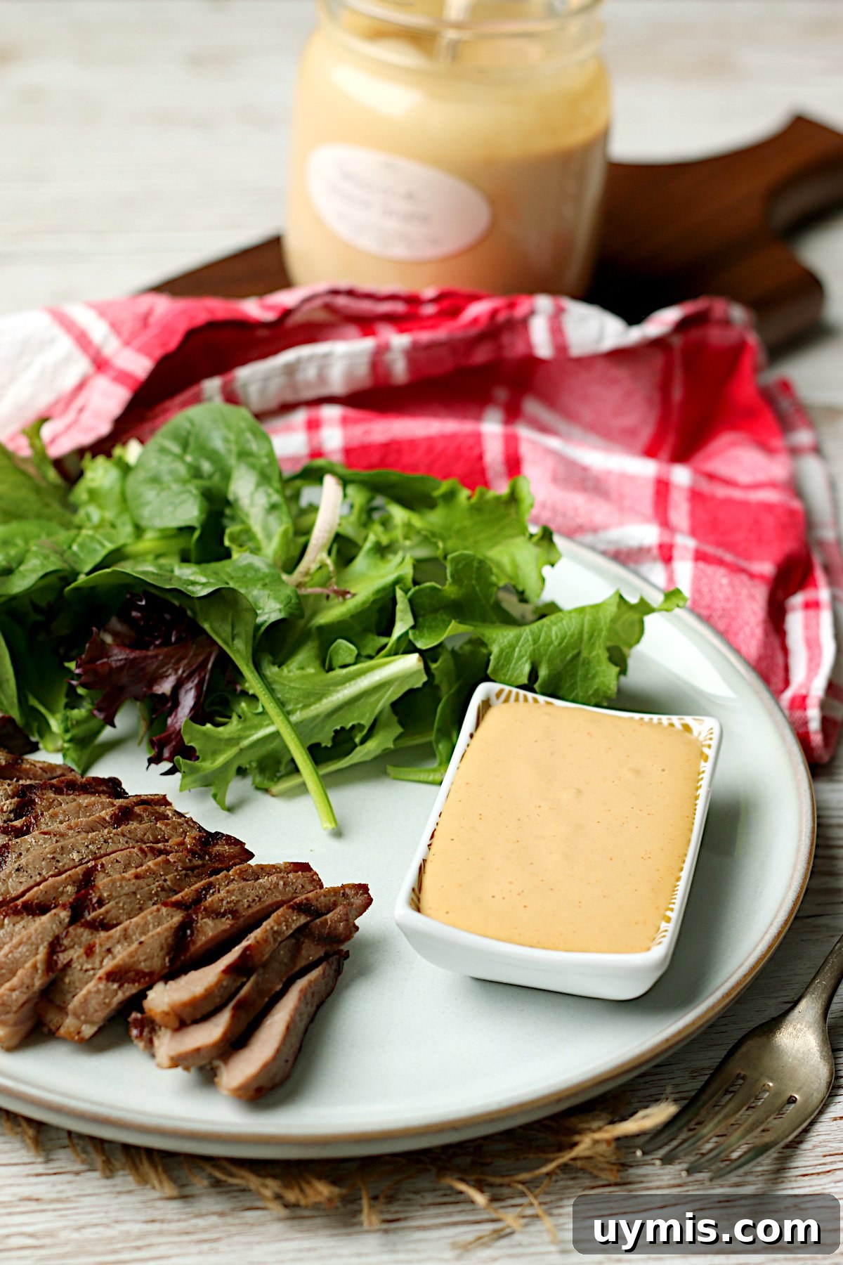 Sesame Steak Sauce Recipe Sawmill Copycat 4 Sliced grilled steak with salad and a small dish of Sesame Steak Sauce on a white plate.