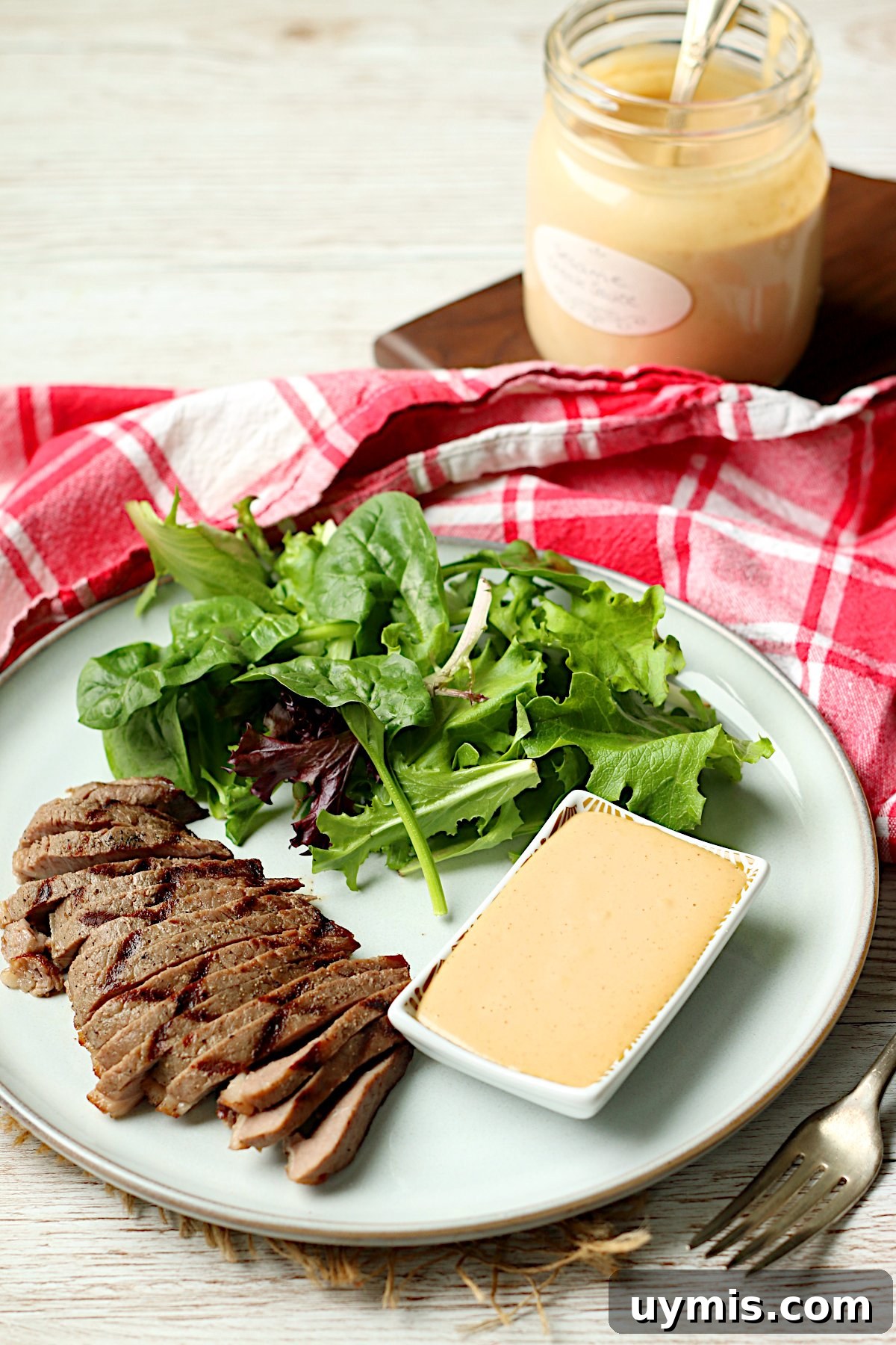 Sesame Steak Sauce Recipe Sawmill Copycat 5 Sliced grilled steak with salad and a small dish of Sesame Steak Sauce on a white plate.
