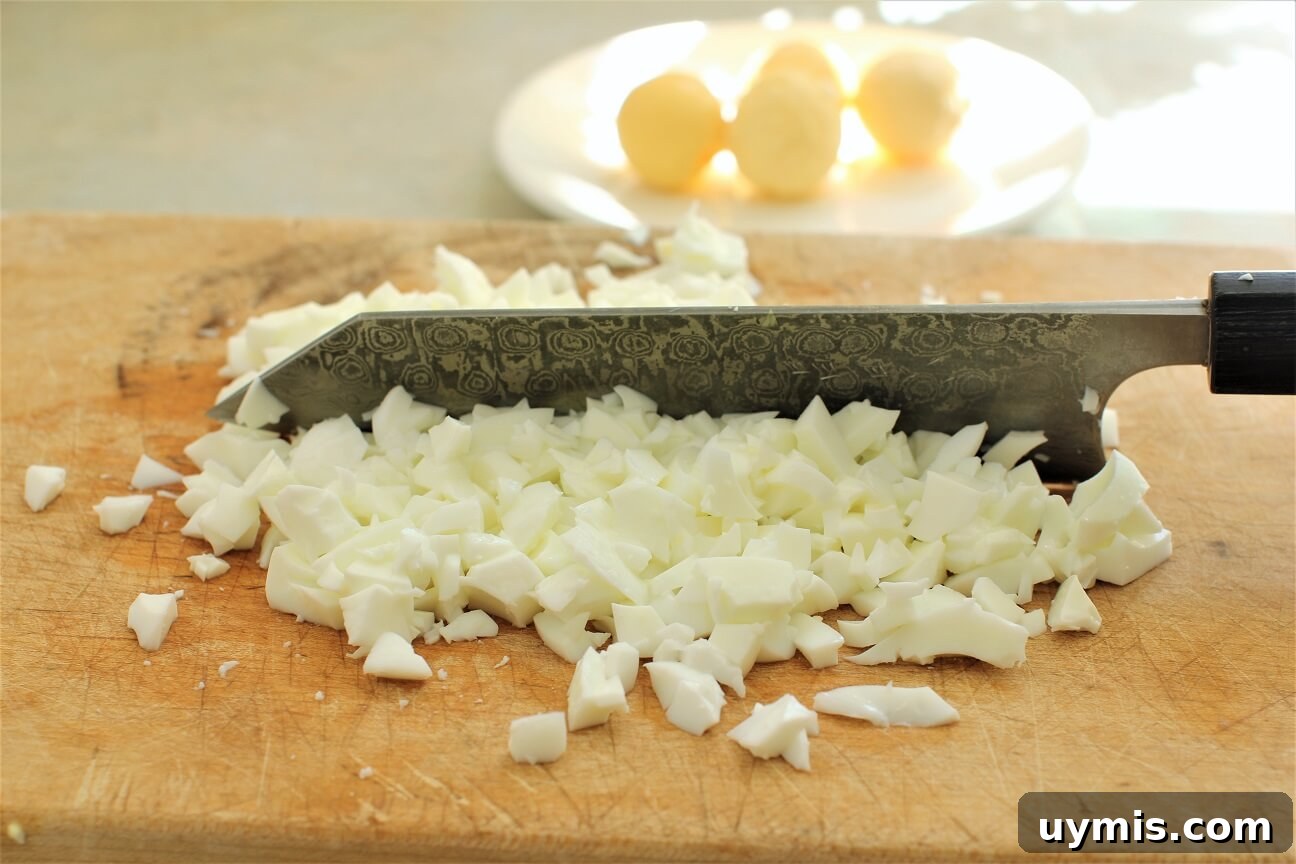 Spring Chive and Egg Pasta Salad Recipe 11 Chopping boiled egg whites on a cutting board for the Chive & Egg Pasta Salad
