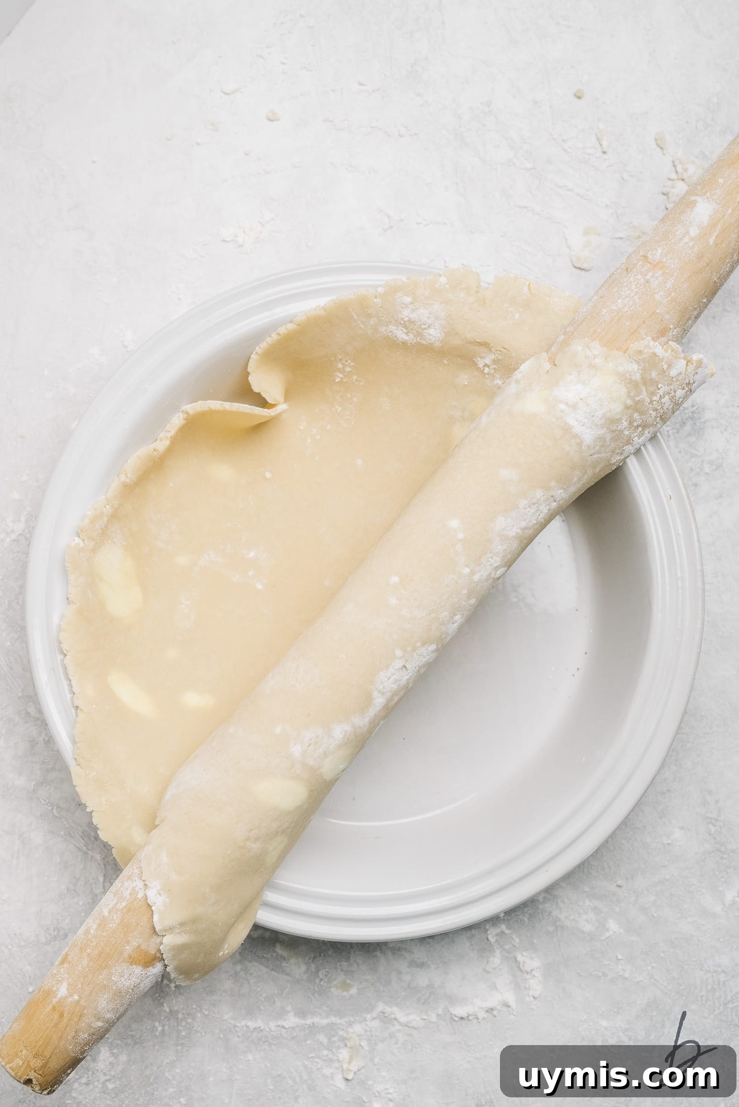 pie crust on rolling pin transferred to pie plate.