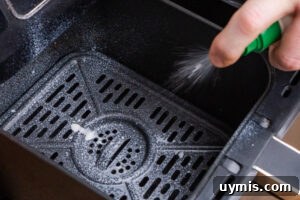 Crispy Air Fryer Sweet Potato Fries 11 Spraying oil into an air fryer basket