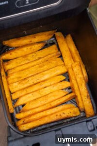 Crispy Air Fryer Sweet Potato Fries 13 Air Fryer Sweet Potato Fries being turned over in an air fryer basket