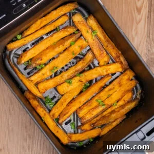 Crispy Air Fryer Sweet Potato Fries 3 Cooked Air Fryer Sweet Potato Fries in an air fryer basket with chopped parsley sprinkled over the top