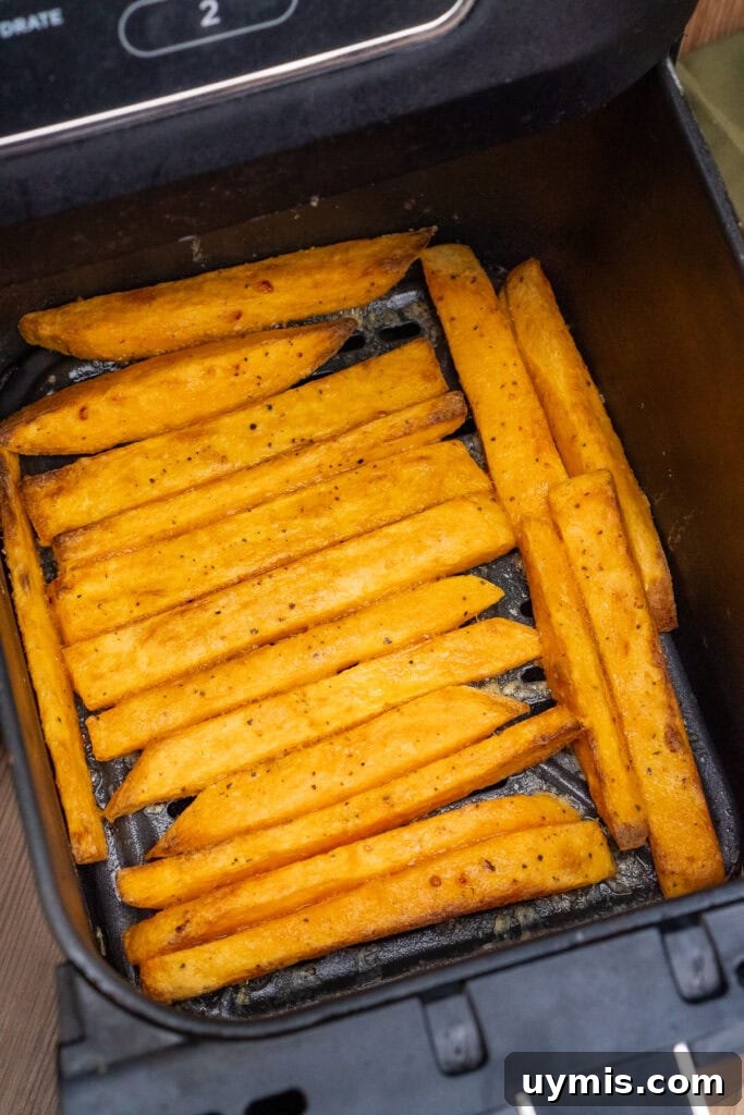 Crispy Air Fryer Sweet Potato Fries 29 Air Fryer Sweet Potato Fries being turned over in an air fryer basket