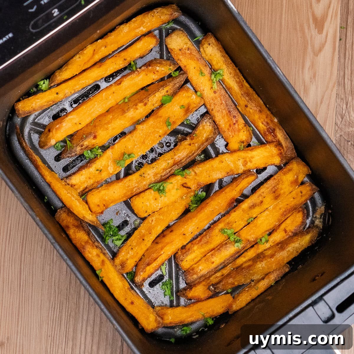 Crispy Air Fryer Sweet Potato Fries 30 Cooked Air Fryer Sweet Potato Fries in an air fryer basket with chopped parsley sprinkled over the top