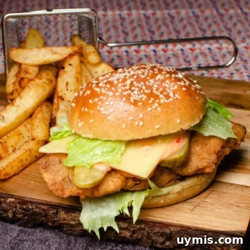 Spicy Chicken Burger on a wooden board served with chips behind the burger