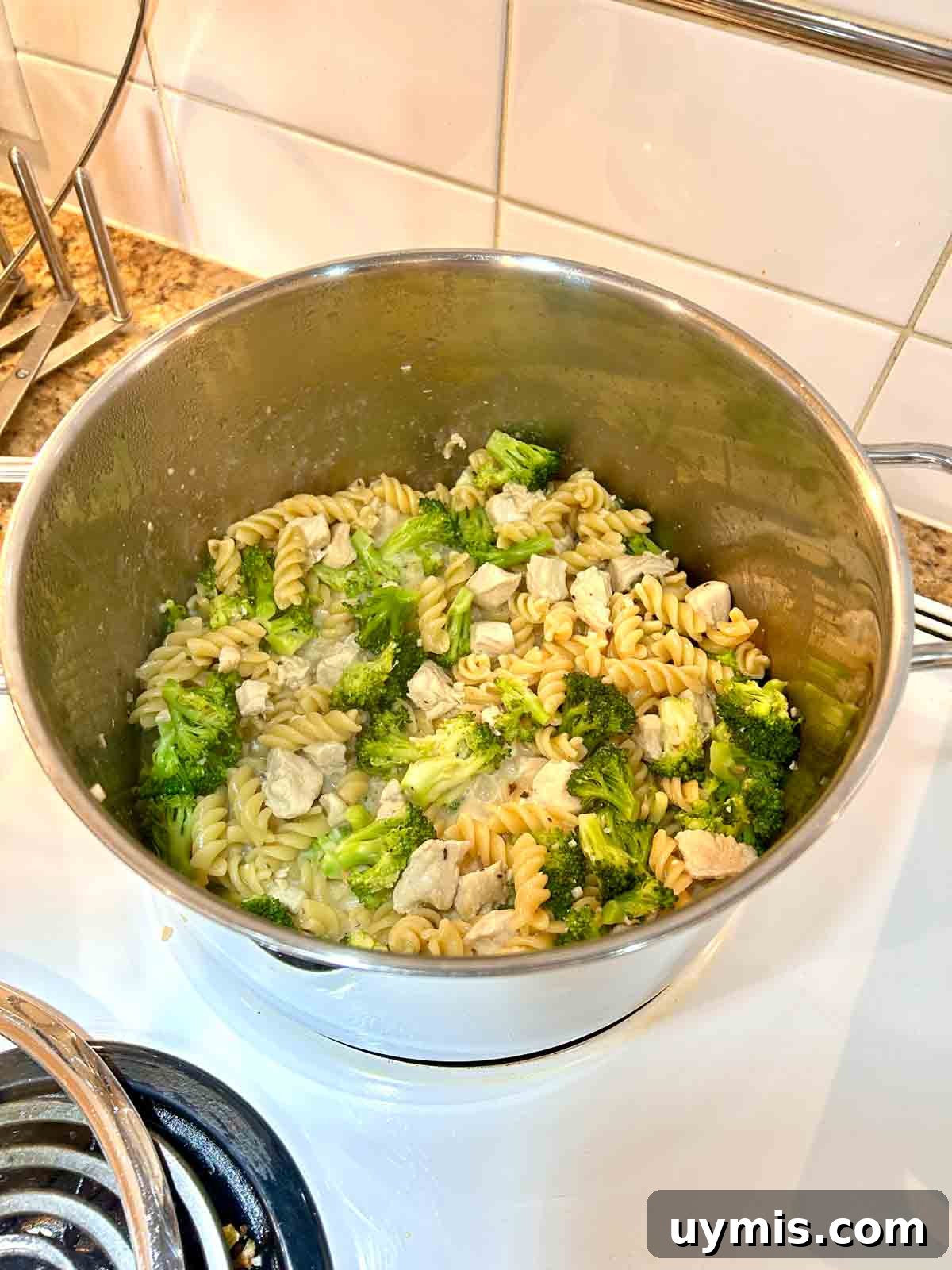 Creamy One Pot Chicken and Broccoli Pasta 7 sauce being thickened in pot.