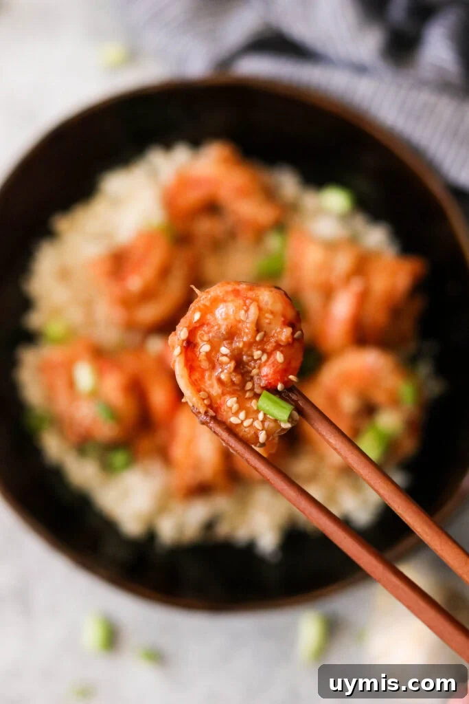 Asian Chili Garlic Shrimp - Paleo Whole30 Recipe 5 Lifting a shrimp in garlic chili sauce with chopsticks