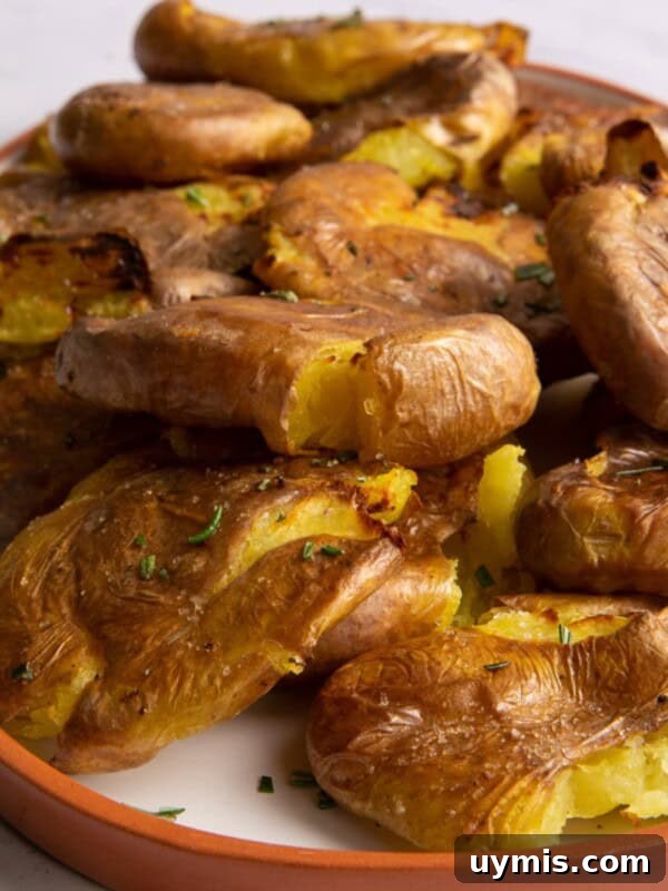 close up of smashed potatoes on white plate with orange edge.