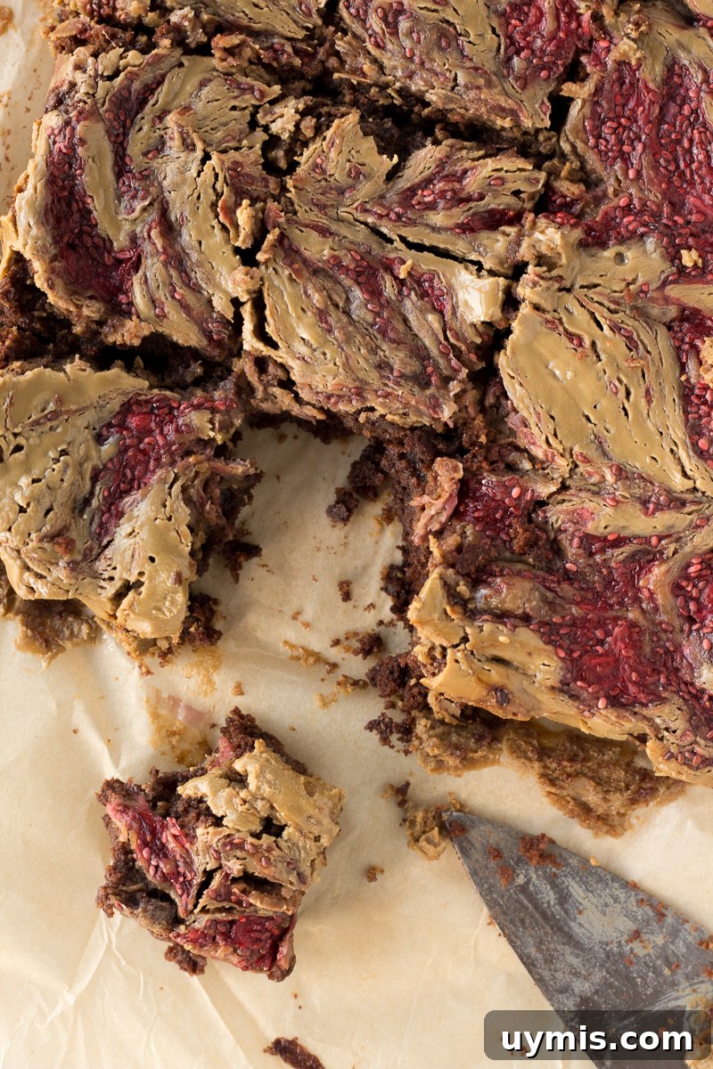 SunButter and Jelly Brownies 2 SunButter & Jelly Brownies cut into squares on parchment paper with a knife