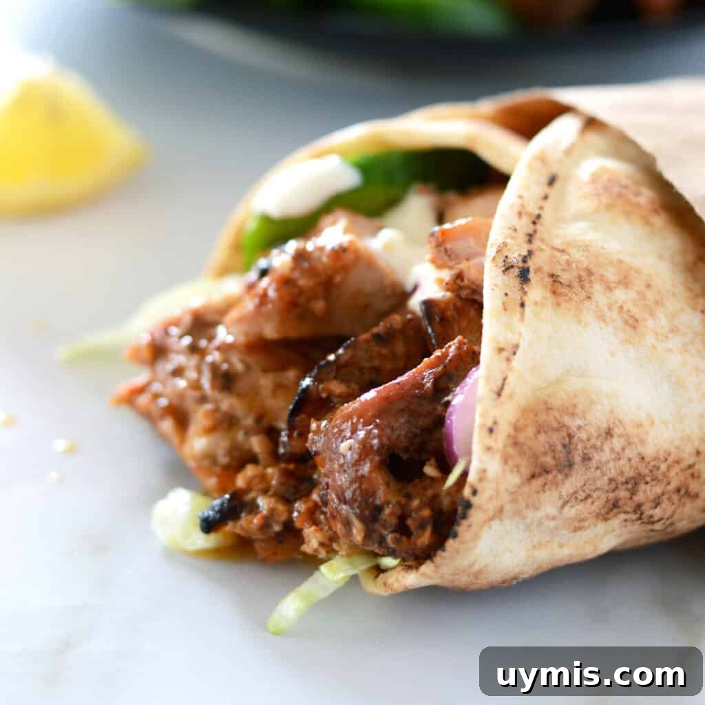 53-Recipe Meal Plan: Weekly Menus and Shopping List 13 A close up picture of a chicken shawarma wrap placed on a awhite countertop with a lemon wedge on the side.