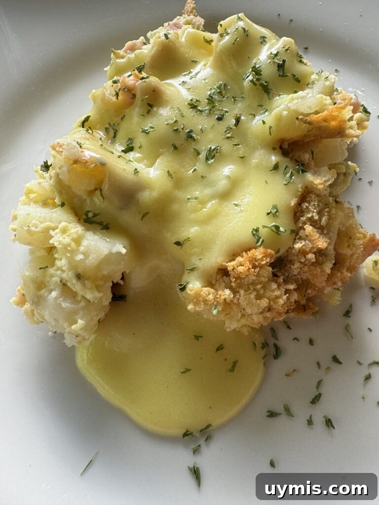Baked Eggs Benedict Hash Brown Casserole 6 A slice of Egg Benedict Hash Brown Casserole with sauce.