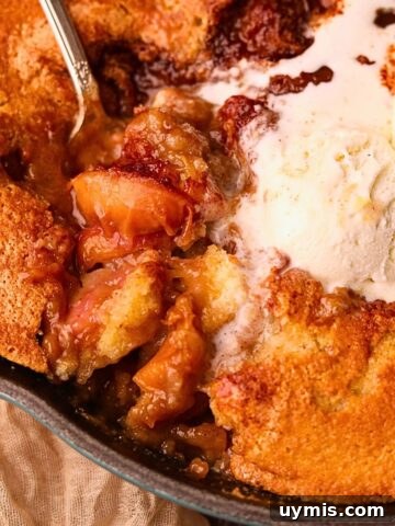 Southern skillet, peach cobbler with a serving spoon to show detail.