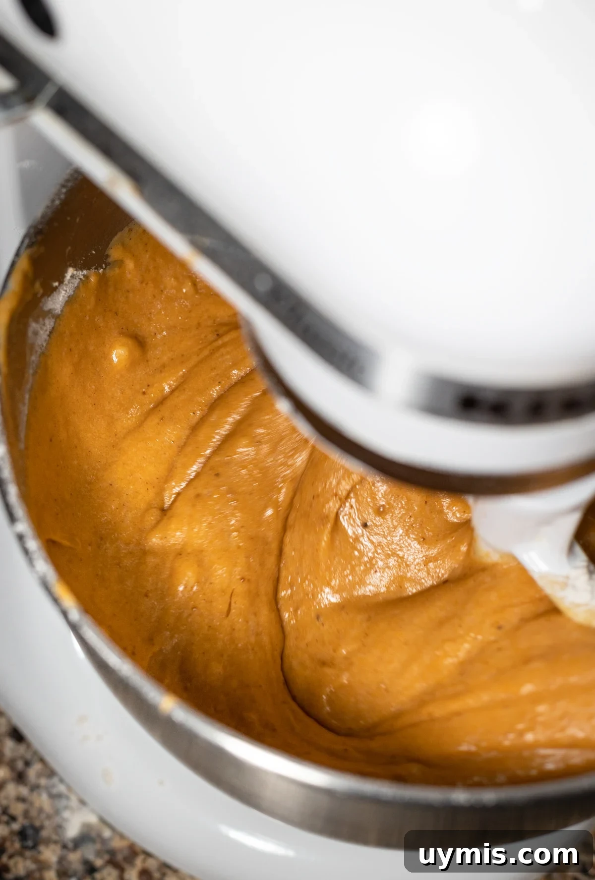 Standing mixer combining wet and dry ingredients for pumpkin banana bread.
