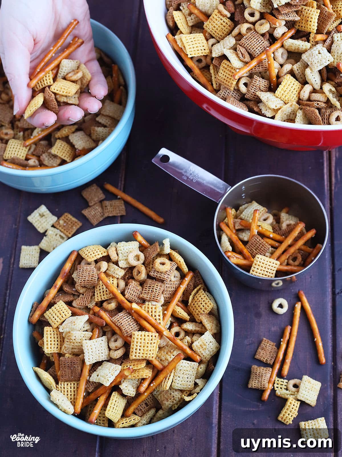 Crispy Oven Baked Chex Mix with Bacon Drippings 9 Individual bowl full of chex mix with a metal measuring cup, with a serving bowl full of chex mix to the side.