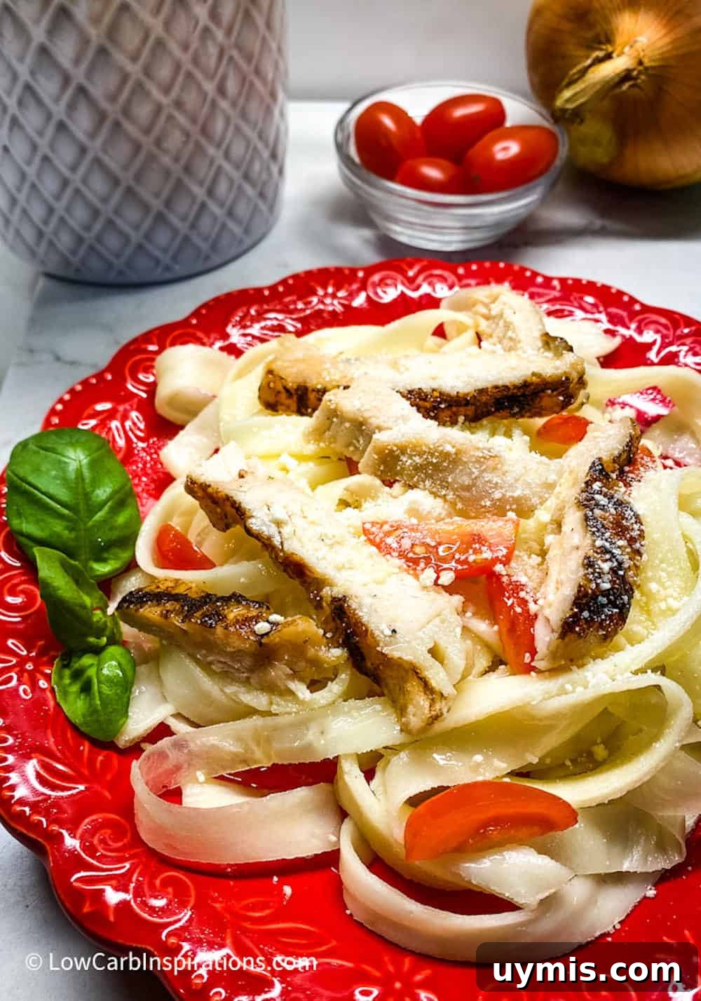 2 Ingredient Keto Pasta Recipe for Low Carb Noodles 5 Keto pasta noodles served with chicken, tomatoes and basil served on a red plate.