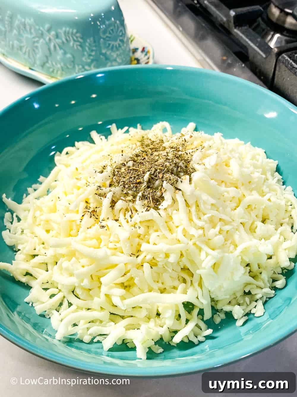 2 Ingredient Keto Pasta Recipe for Low Carb Noodles 9 Blue bowl of shredded mozzarella cheese topped with seasonings.