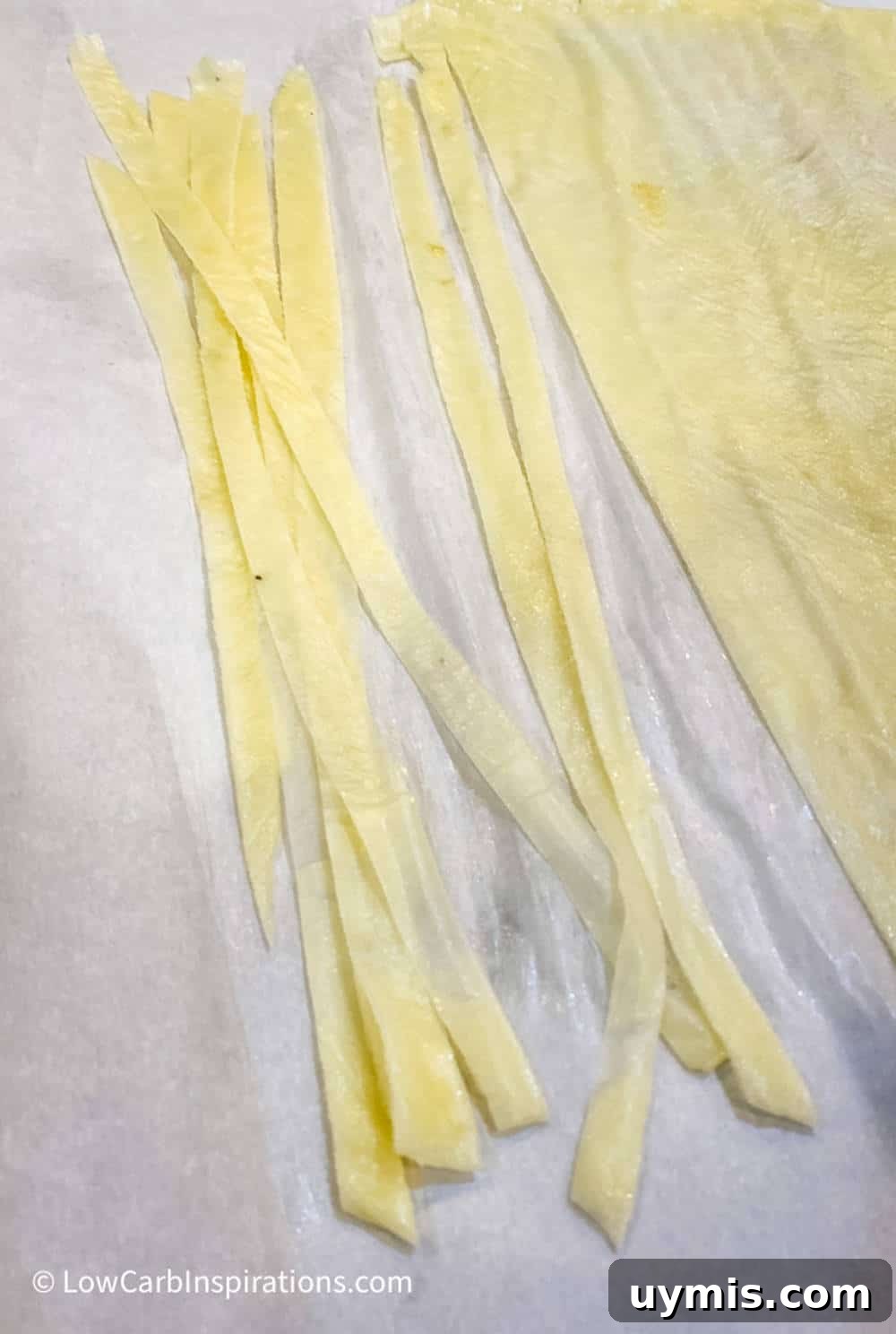 2 Ingredient Keto Pasta Recipe for Low Carb Noodles 10 Long strands of keto pasta noodles on parchment paper