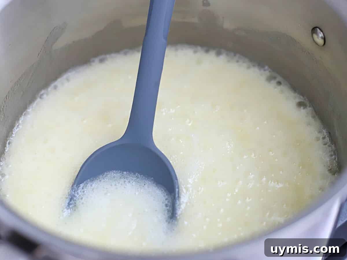 Sugar, milk, and butter boiling in a pot.