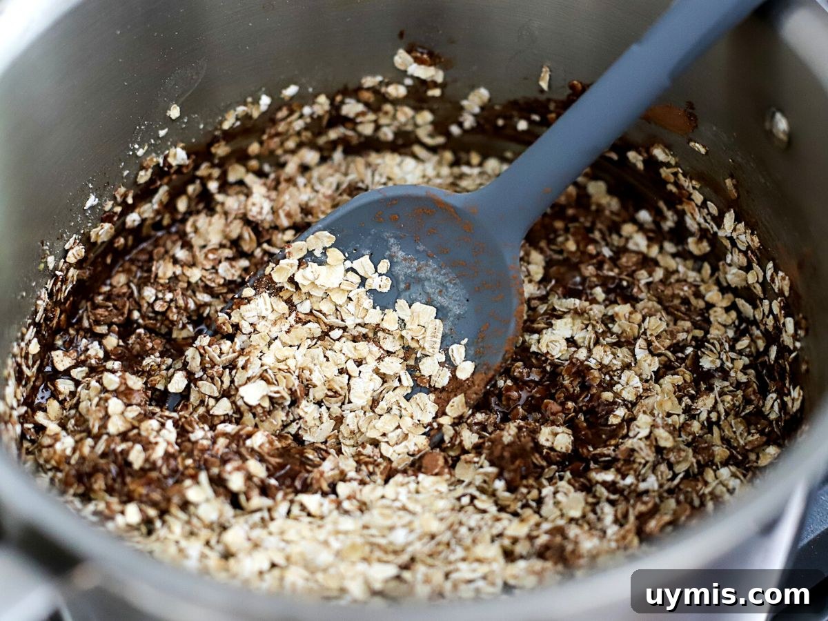 Oats and chocolate being mixed into no-bake cookie batter.