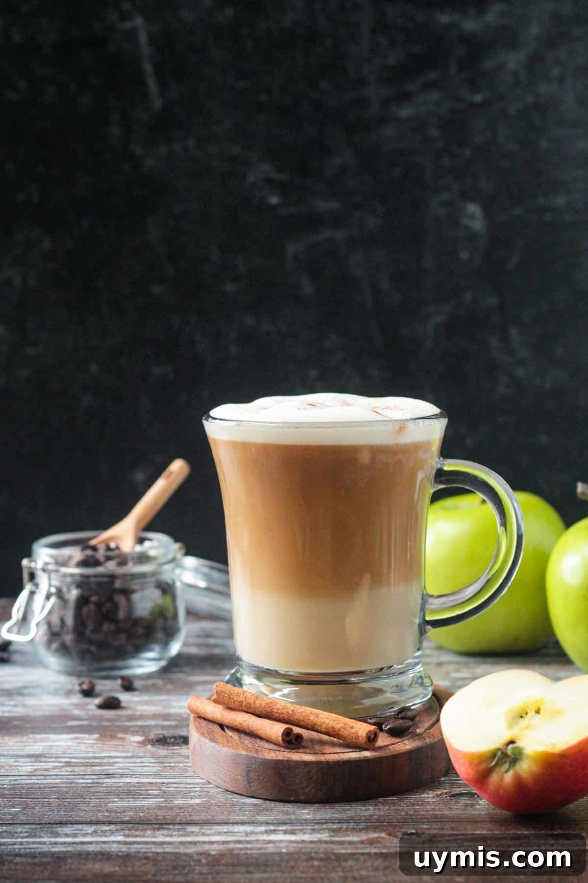 Two cinnamon sticks in front of a macchiato.
