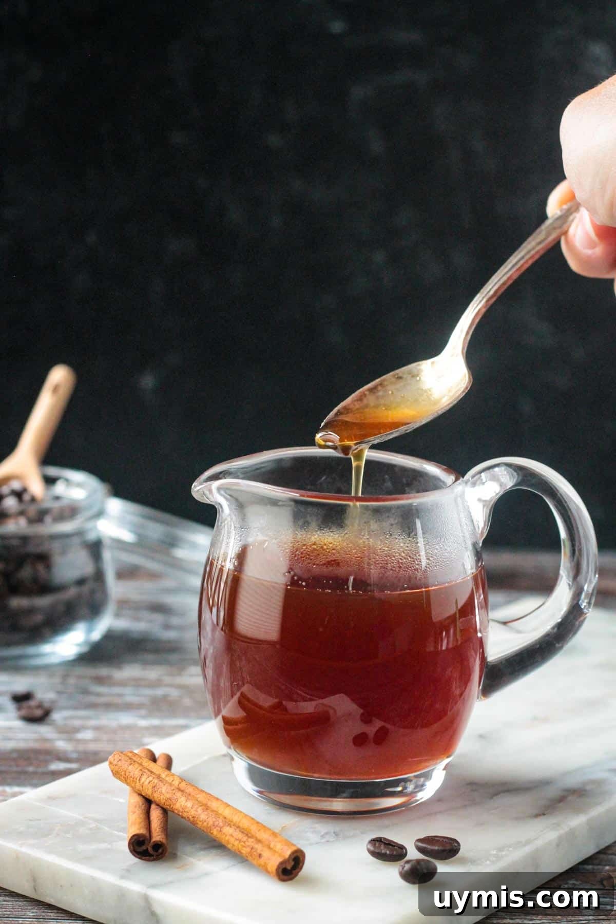 Apple brown sugar syrup drizzled off of a spoon into a glass.