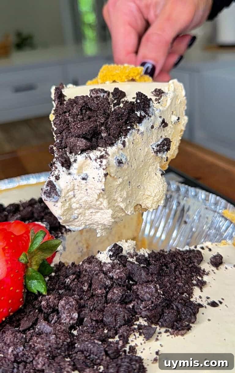 Why I Switched to Caraway Cookware: One-Pan Dinner for Two 7 A hand lifts a large, creamy slice of pie topped with crushed chocolate cookies from a pie tin.
