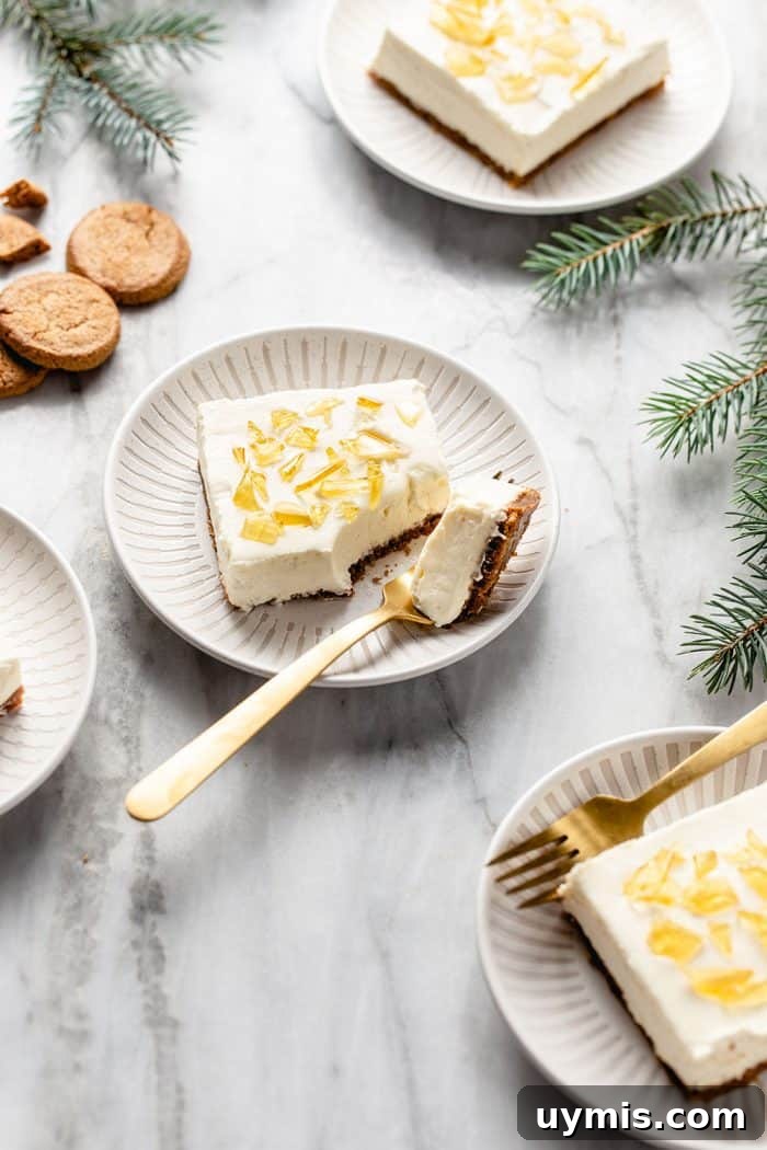 White plates holding slices of no-bake cheesecake bars arranged on a marble counter among sprigs of greenery