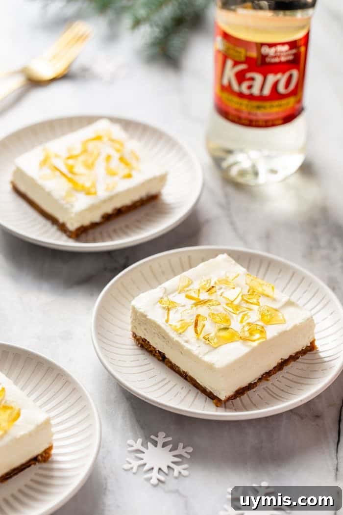Two white plates with slices of no-bake cheesecake bars topped with cracked sugar. A bottle of corn syrup is in the background