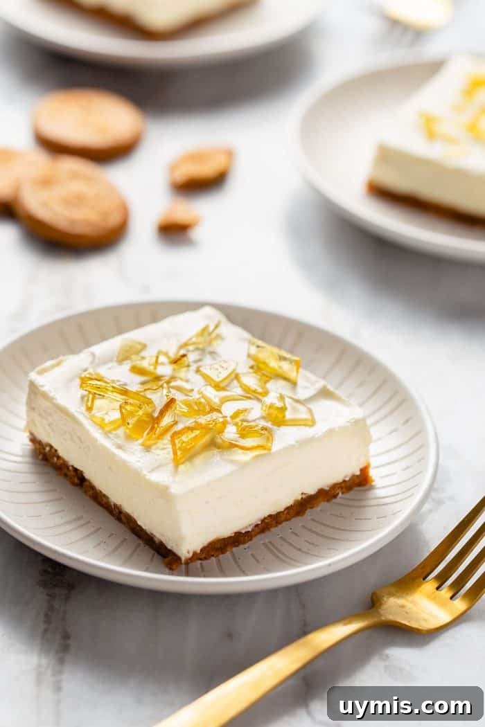 No-bake cheesecake bar with cracked sugar topping on a white plate next to a gold fork