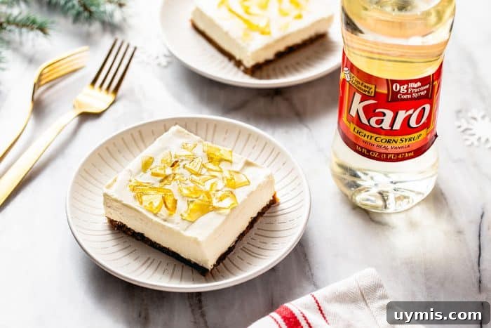 No-bake cheesecake bar on a white plate with a second bar and a bottle of corn syrup in the background