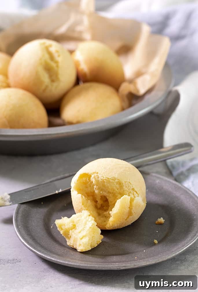 A small plate with pan de bono broken, with a butter knife