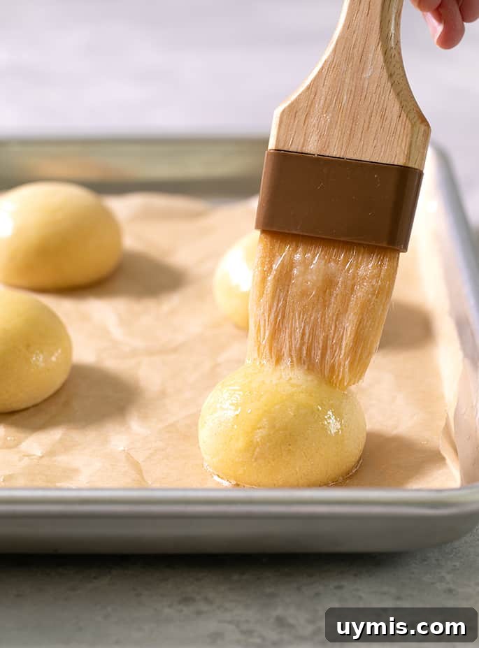 A pastry brush on top of a raw ball of pan de bono