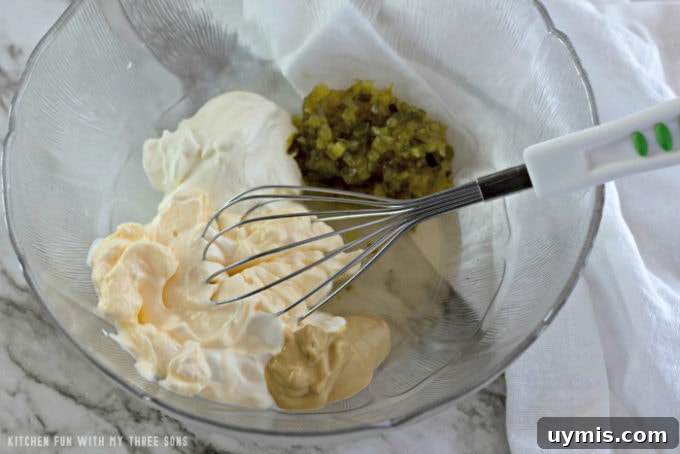 Whisking together salad dressing ingredients in a clear bowl on a marble counter