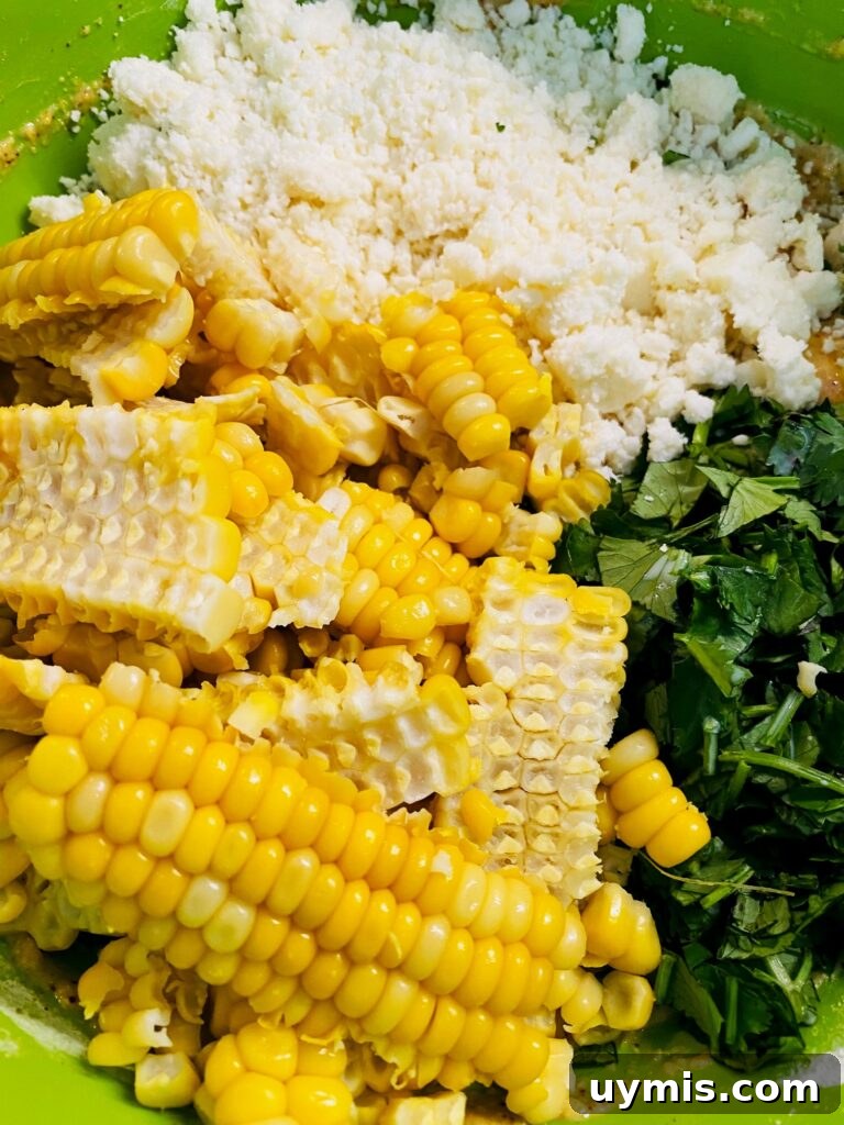 Blackstone Street Corn Fritters Recipe 4 adding corn cilantro and cotija cheese to the bowl