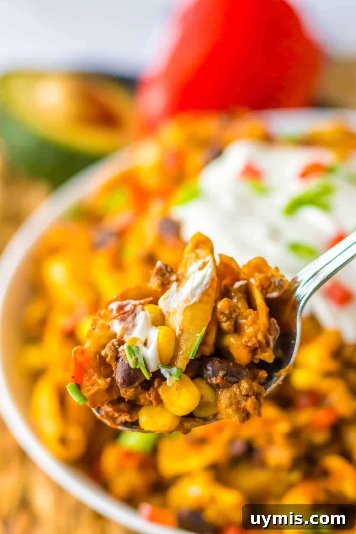 Serving spoon scooping cheesy taco pasta from a slow cooker.