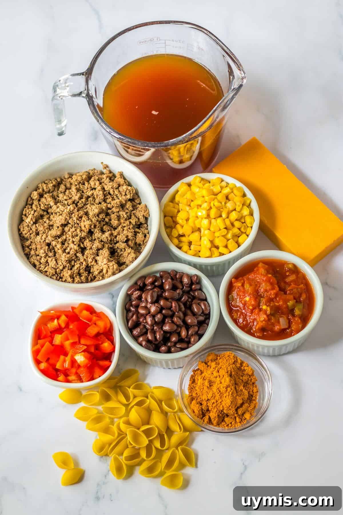 Ingredients for slow cooker taco pasta including ground beef, salsa, black beans, corn, taco seasoning, cheese, and pasta.