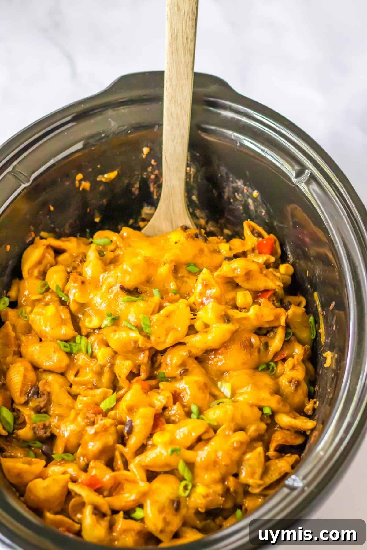 Overhead view of cheesy crockpot taco pasta made with ground beef, black beans, corn, and pasta.