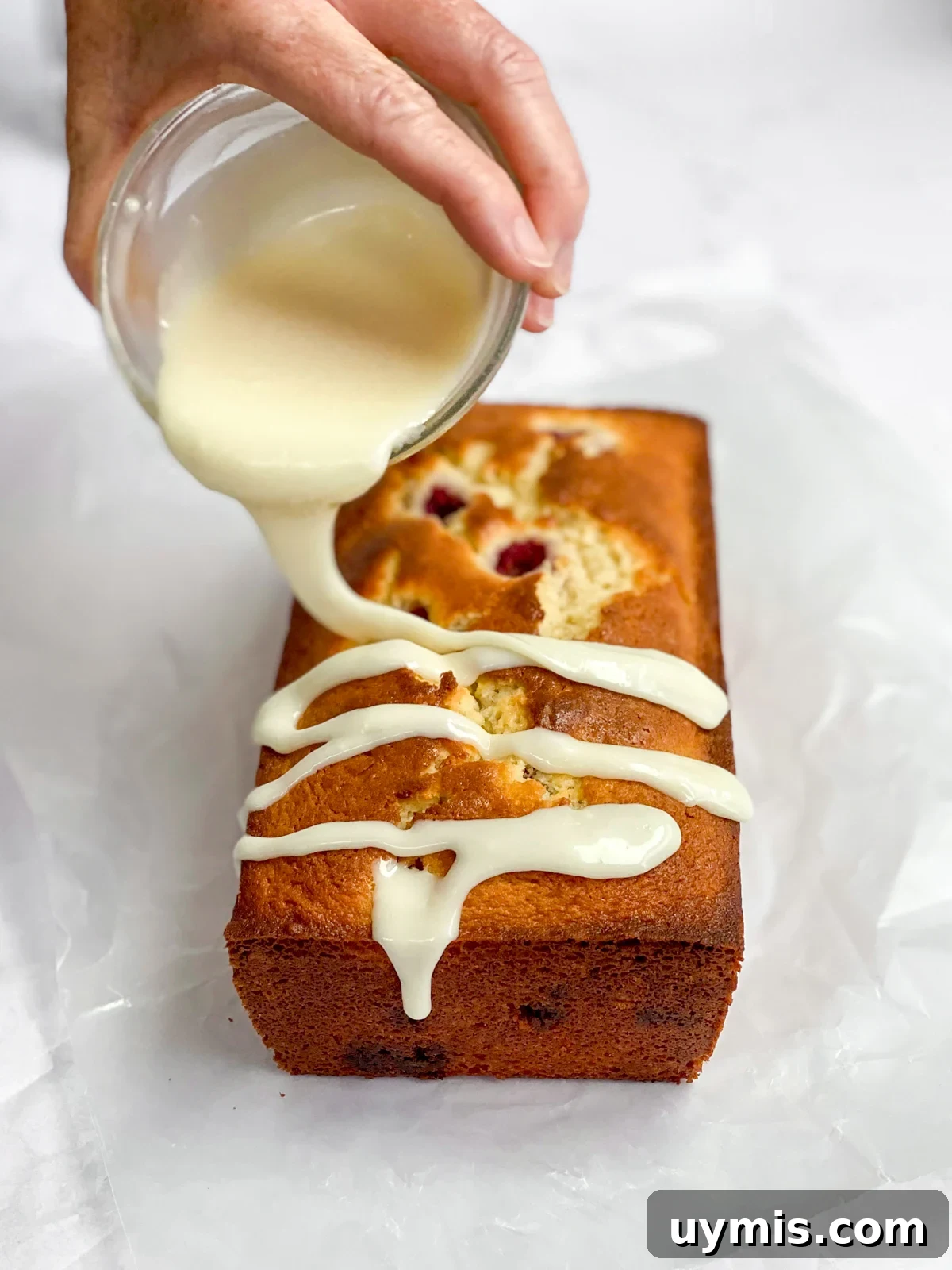 White Chocolate Raspberry Loaf Cake 13 pouring glaze over the loaf cake