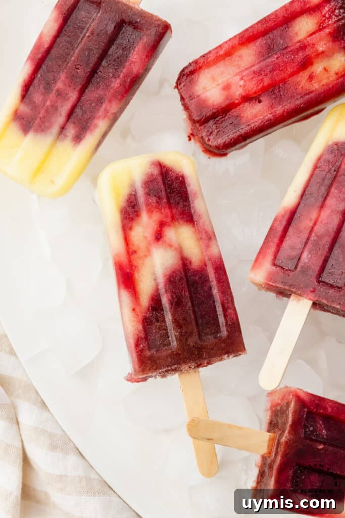 Homemade Fruit Popsicles Recipe for Refreshing Summer Treats 2 swirled pineapple cherry popsicles on ice.