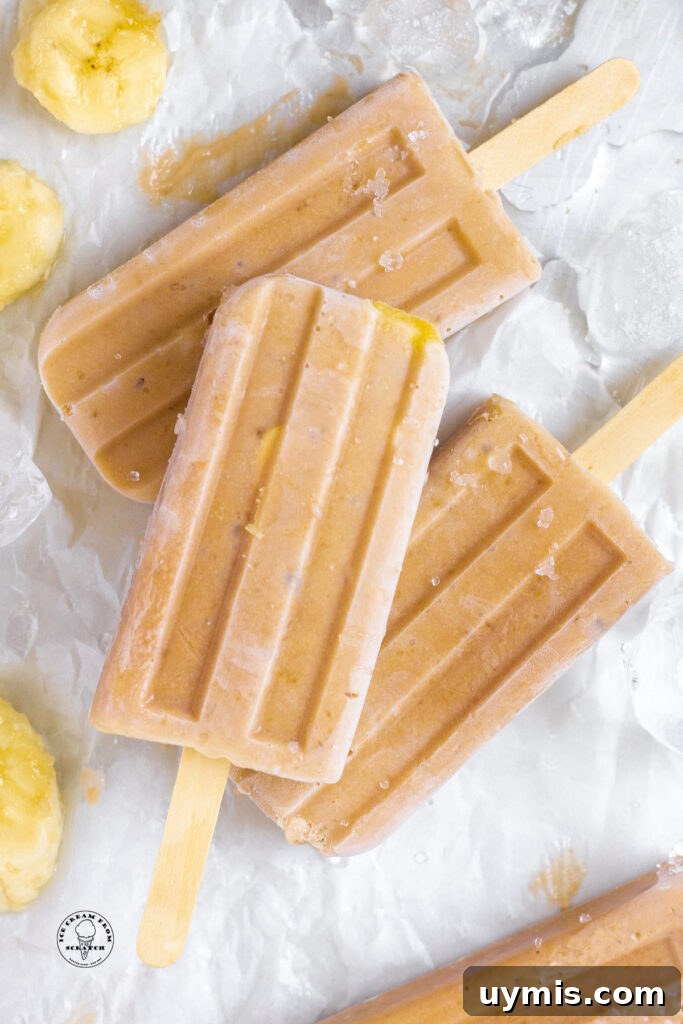 Homemade Fruit Popsicles Recipe for Refreshing Summer Treats 4 Three banana popsicles on a piece of parchment paper with slices of ripe banana